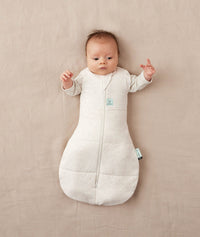 Newborn wearing an ergoPouch Cocoon Swaddle Bag 3.5 TOG Oatmeal Marle with arms out