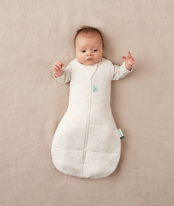 Newborn wearing an ergoPouch Cocoon Swaddle Bag 3.5 TOG Oatmeal Marle with arms out