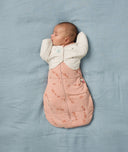 Baby is sleeping on a soft blue blanket, wearing a Butterfly Cardi over a Cocoon Swaddle Bag.