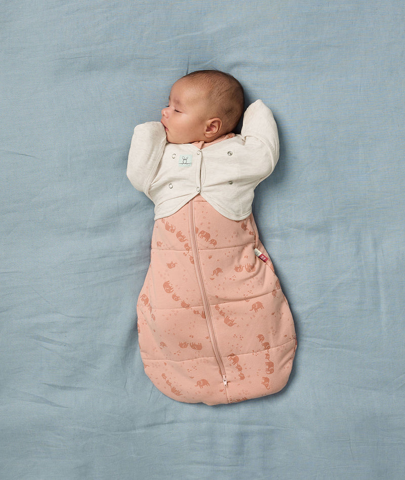 Baby is sleeping on a soft blue blanket, wearing a Butterfly Cardi over a Cocoon Swaddle Bag.