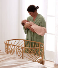 Mum wearing a a Matchy Matchy Robe, holding newborn wearing an ergoPouch Cocoon Swaddle Bag 1.0 TOG Daisies