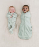 Two babies, one wearing a Cocoon Swaddle Bag 0.2 TOG Sage and the other in a Layer
