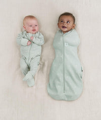 Two babies, one wearing a Cocoon Swaddle Bag 0.2 TOG Sage and the other in a Layer