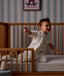 Child sitting on his bed with a Organic Toddler Pillow and Case Daydream, wearing a Sleep Suit Bag 1.0 TOG Daydream.