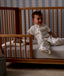 Child sitting in a wooden crib with Organic Toddler Pillow and Case Daydream, wearing a Sleep Suit Bag 1.0 TOG Daydream.