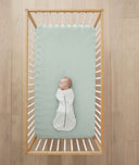 Baby laying in cot on ergoPouch Organic Fitted Sheet Sage