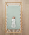 Baby laying in cot on ergoPouch Organic Fitted Sheet Sage