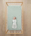 Baby laying in cot on ergoPouch Organic Fitted Sheet Sage