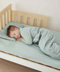 Toddler sleeping on bed made with ergoPouch Organic Fitted Sheet Sage