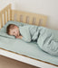 Toddler sleeping on bed made with ergoPouch Organic Fitted Sheet Sage