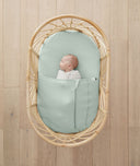 Baby resting in bassinet made with ergoPouch Organic Fitted Sheet Sage
