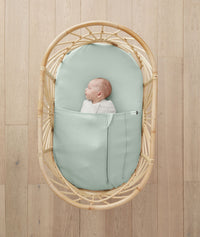 Baby resting in bassinet made with ergoPouch Organic Fitted Sheet Sage