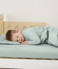 Toddler sleeping on bed made with ergoPouch Organic Fitted Sheet Sage