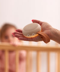 Mum holding an ergoPouch white noise machine to help soothe her baby to sleep.