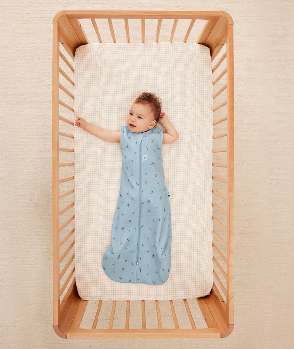 Baby wearing a blue ergoPouch sleeping bag that is made from organic, breathable materials.