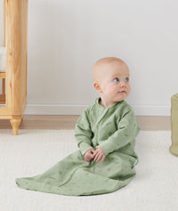 Newborn sitting, wearing an ergoPouch Jersey Sleeping Bag 1.0 TOG Sleeved Willow