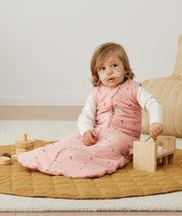 A child playing with toys in an ergoPouch Sleeping Bag 2.5 TOG Daisies layered with a Long Sleeve Layer 1.0 TOG Oatmeal Marle underneath to keep warm in the winter months. 