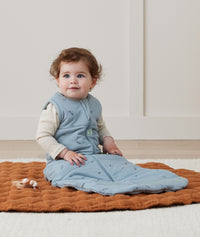 Newborn sitting, wearing an ergoPouch Jersey Sleeping Bag 2.5 TOG Dragonflies