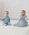 Two infants sitting on the floor both wearing ergPouch Dragonflies, one in a Long Sleeve Layer 1.0 TOG and the other in a Sleeping Bag 2.5 TOG, perfect layering for the colder months