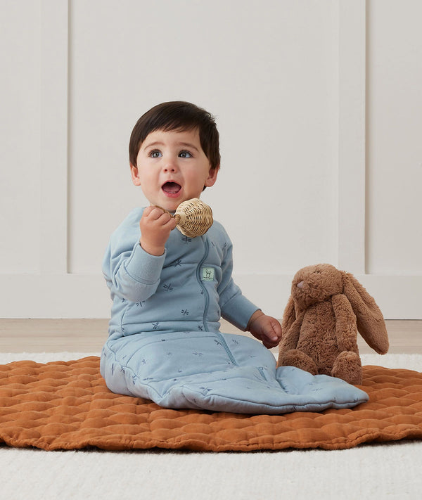 Newborn sitting, wearing an ergoPouch Jersey Sleeping Bag 2.5 TOG Sleeved Dragonflies