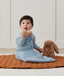 Newborn sitting, wearing an ergoPouch Jersey Sleeping Bag 2.5 TOG Sleeved Dragonflies