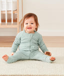 Newborn sitting, wearing an ergoPouch Long Sleeve Layer 0.2 TOG Sage