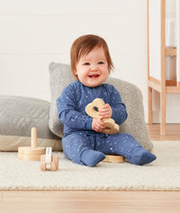 Newborn sitting, wearing an ergoPouch Long Sleeve Layer 0.2 TOG Night Sky