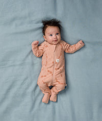 Baby lying on a soft blue sheet, wearing an ergoPouch Long Sleeve Layer 1.0 TOG Elephant Parade