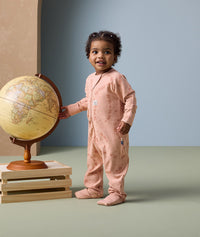 Infant standing next to a globe, dressed in ergoPouch Long Sleeve Layer 1.0 TOG Elephant Parade