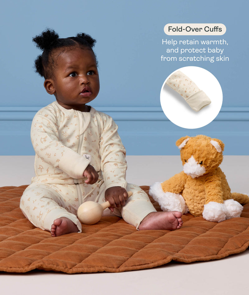 Baby sitting on a mat in a cream Long Sleeve Layer next to a plush toy, with a feature highlight on 