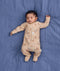 Sleeping baby lying on a blue fabric background wearing a beige patterned Long Sleeve Layer with fold-over cuffs
