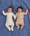 Two babies lying side by side wearing ergoPouch Long Sleeve Layers in Lullaby and Melody