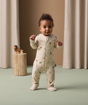 Infant standing in ergoPouch Long Sleeve Layer 1.0 TOG Savannah with foot cuffs folded over to retain warmth and protect skin.