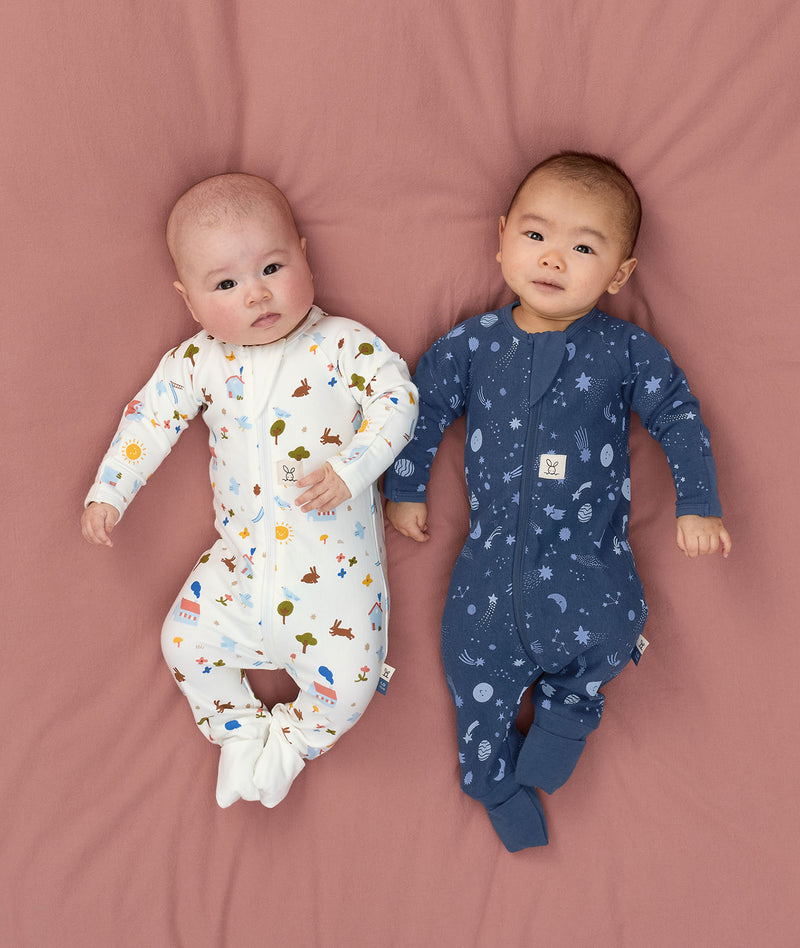 Two babies lying in ergoPouch Long Sleeve Layer 1.0 TOG Daydream and Starbeam