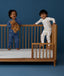 Two children standing in a crib wearing ergoPouch Long Sleeve Layer 1.0 TOG Daydream and Starbeam