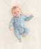 Baby is lying on a neutral coloured blanket, wearing a blue Long Sleeve Layer with dragonfly prints.