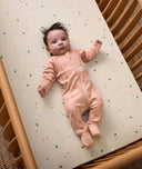 Baby lying in a cot wearing a Long Sleeve Layer 1.0 TOG with cute elephant prints.