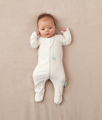 Baby lying on a soft pink blanket dressed in an ergoPouch Long Sleeve Layer with its foot cuffs folded over for added warmth and protection.