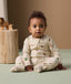 Infant sitting on the floor in ergoPouch Long Sleeve Layer 1.0 TOG Savannah with foot cuffs folded over.