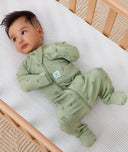 Baby lying in a cot wearing an ergoPouch Long Sleeve Layer with its hand and foot cuffs folded over.
