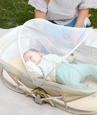 Baby inside a in an ergoPouch Easy Sleep Portable Crib with the mosquito net closed