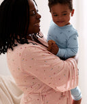 Mum wearing a an ergoPouch Matchy Matchy Robe Daisies, holding a child