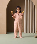 A preschooler holding toys in both hands is wearing an ergoPouch Sleep Onesie 2.5 TOG, with its foot cuffs folded over for extra warmth and protection.