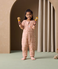 A preschooler holding toys in both hands is wearing an ergoPouch Sleep Onesie 2.5 TOG, with its foot cuffs folded over for extra warmth and protection.