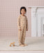 Preschooler wearing a beige patterned 2.5 TOG Sleep Onesie, standing while holding the string of a small wooden pull-along horse toy.