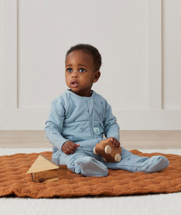 Baby sitting, wearing an ergoPouch Sleep Onesie 2.5 TOG Dragonflies