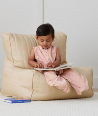 Toddler reading a book whilst wearing ergoPouch Sleep Suit Bag 0.2 TOG Daisies