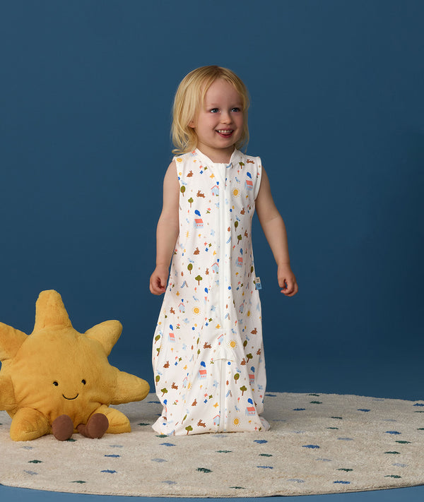 Smiling toddler wearing an ergoPouch Jersey Sleep Suit Bag 0.2 TOG Daydream, a sleeping bag that converts to a sleep suit with legs