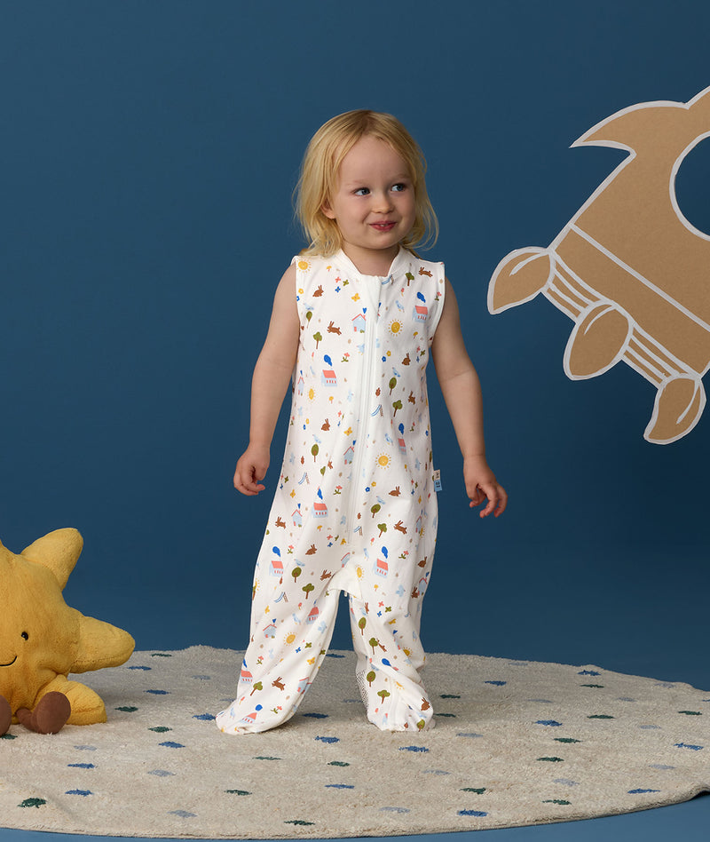 Smiling toddler wearing an ergoPouch Jersey Sleep Suit Bag 0.2 TOG Daydream, a sleeping bag that converts to a sleep suit with legs