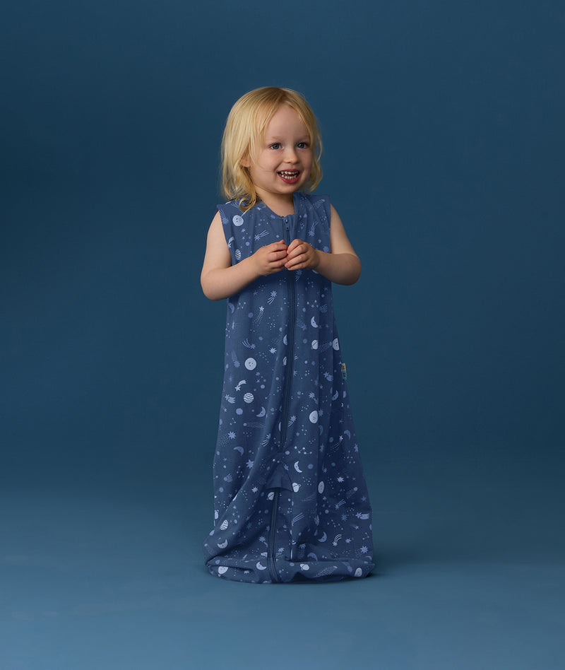 Smiling toddler wearing an ergoPouch Jersey Sleep Suit Bag 0.2 TOG Starbeam, a sleeping bag that converts to a sleep suit with legs.